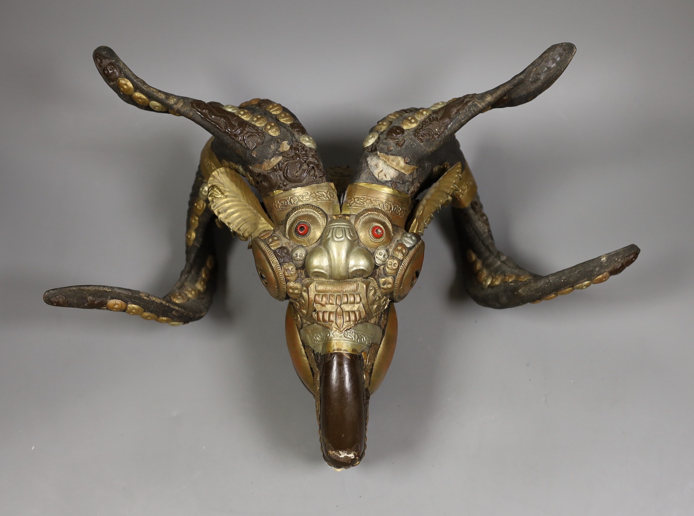A Buddhist decorated ram's skull with brass decor, 20cm tall